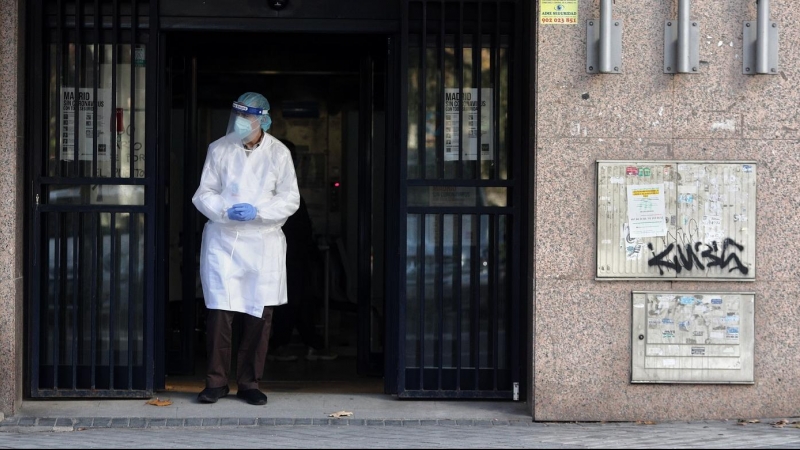 20/11/2020- Una trabajadora sanitaria sale de un portal de Madrid vistiendo un EPI (ARCHIVO)