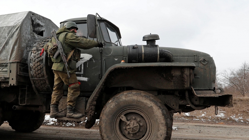 Un miembro del servicio de las tropas pro-rusas en uniforme sin insignias se encuentra en el escalón de un camión militar en el pueblo de Bugas.