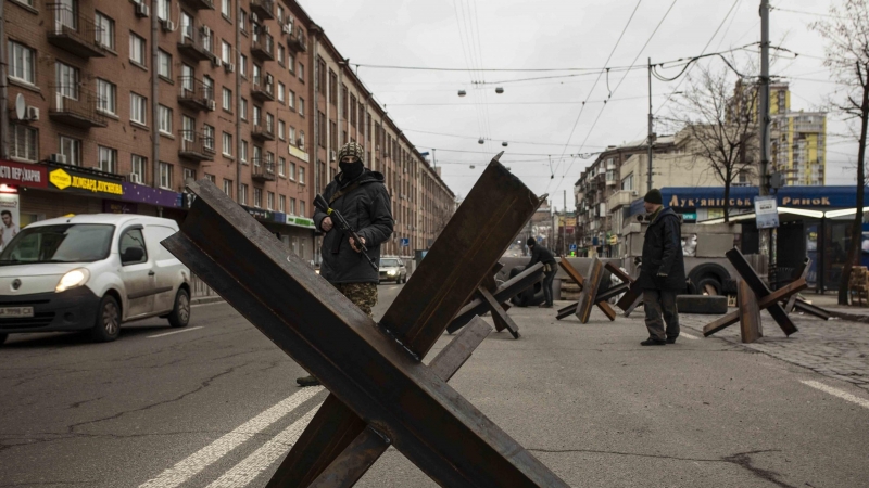 Un voluntario de las Fuerzas de Defensa Territorial de Ucrania controla el tráfico en un puesto de control en Kiev este domingo.