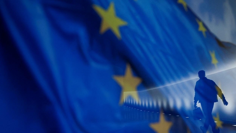 El reflejo de un hombre por un pasillo del Bundestag, en Berlin, sobre una bandera de la UE. REUTERS/Michele Tantussi