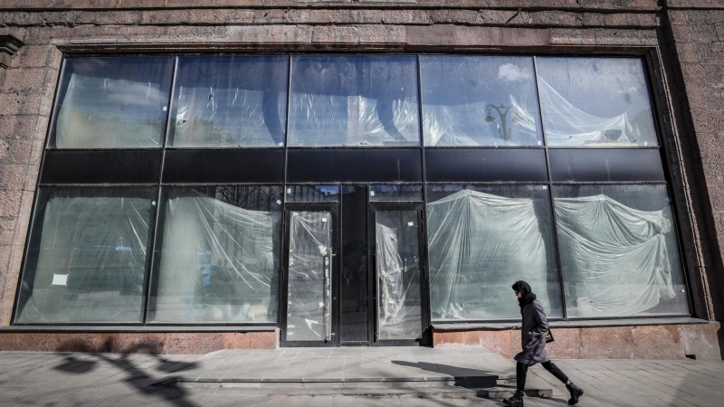 Una mujer rusa camina frente a las ventanas de un espacio comercial vacío en el centro de Moscú, Rusia, el 15 de marzo de 2022.