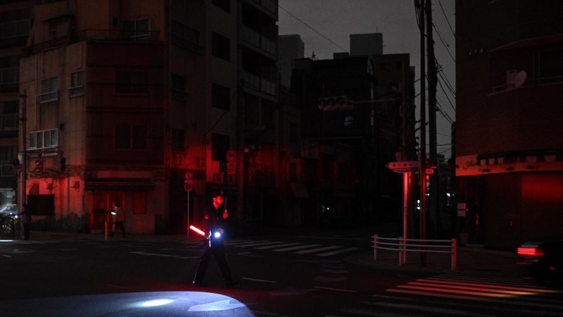 Un policía se encuentra junto a una calle de tráfico directo durante un corte de energía en Tokio a primeras horas del 17 de marzo de 2022, después de que un poderoso terremoto de magnitud 7,3 sacudiera el este de Japón.