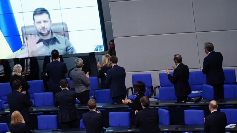 El presidente de Ucrania, Volodymyr Zelensky, saluda mientras recibe aplausos después de pronunciar un discurso en video ante el parlamento alemán.