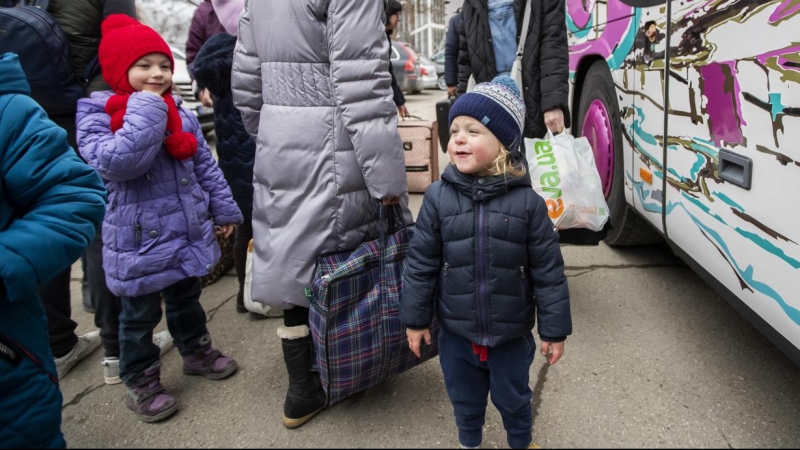 Mujeres y niños que huyen de Ucrania se preparan para tomar un autobús a Alemania, cerca de un centro de clasificación de refugiados en un estadio deportivo en Chisinau, Moldavia.