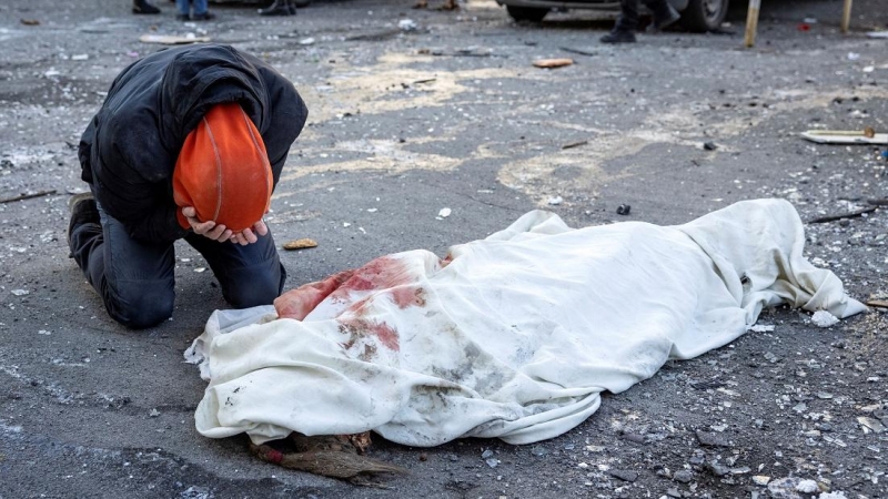 Una persona llora junto a un cuerpo envuelto cerca de un edificio residencial que fue alcanzado por los escombros de un cohete derribado en Kiev, a 17 de marzo de 2022.
