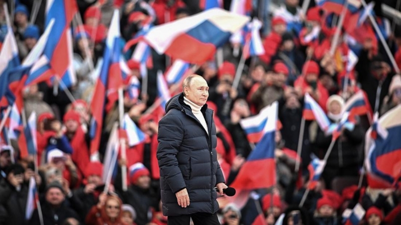 La multitud ondea banderas rusas mientras el presidente ruso Vladimir Putin camina para pronunciar un discurso durante un concierto celebrado para conmemorar el octavo aniversario de la anexión de Crimea por parte de Rusia en el estadio Luzhniki.