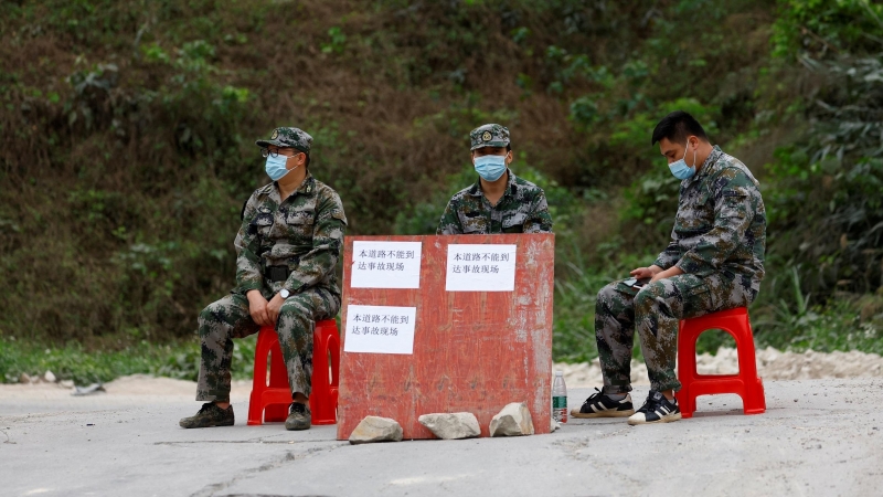 22/3/22-Los miembros de la milicia se sientan en el puesto de control en la carretera junto a la entrada de la aldea de Lu, cerca del lugar donde se estrelló un avión Boeing 737-800 de China Eastern Airlines que volaba de Kunming a Guangzhou, en Wuzhou, R