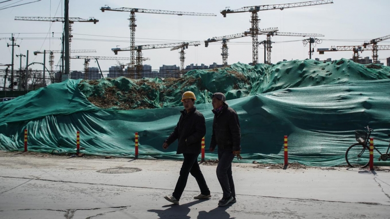 Dos trabajadores migrantes caminan cerca de una obra en Pekín. EFE/EPA/WU HONG
