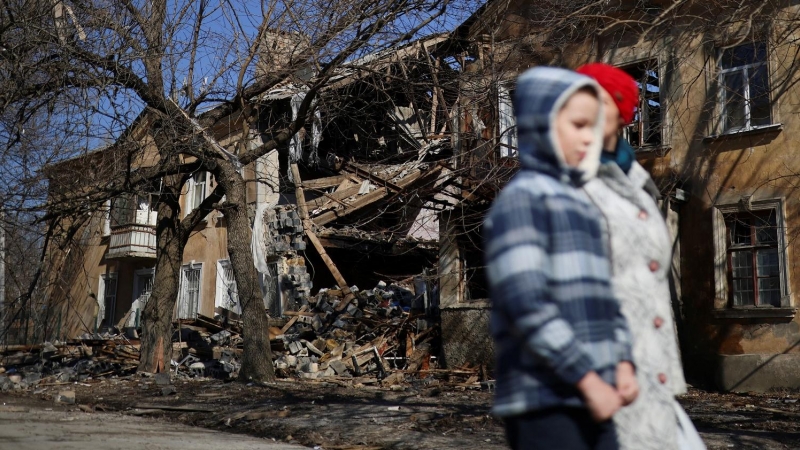 24/03/2022 Natalia y su hijo Micha, de 9 años, caminan frente a un edificio bombardeado en su barrio en Mykolaiv, Ucrania, este 24 de marzo