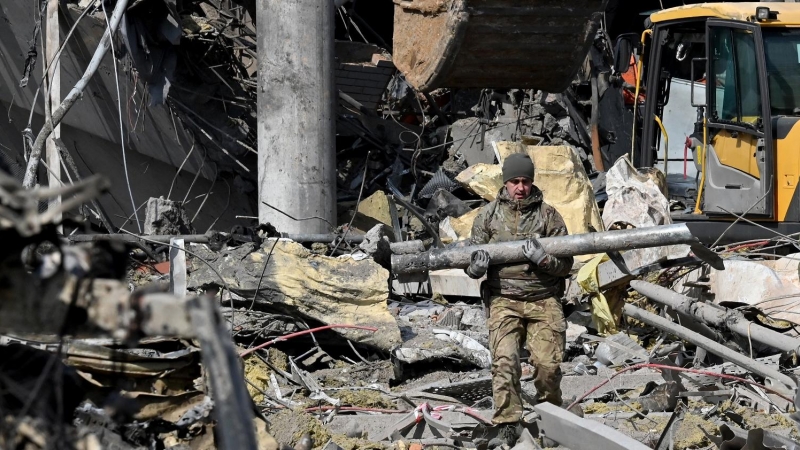 24/03/2022 Un militar ucraniano carga un fragmento de misil mientras sale de un edificio bombardeado de Kiev, a 24 de marzo