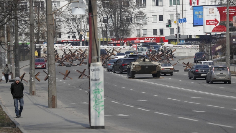 24/03/2022-Los coches transitan en una calle junto a vehículos blindados del ejército cerca de barricadas en las afueras de Kiev, Ucrania, este 24 de marzo