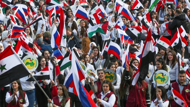 Jóvenes con banderas de Siria y de Rusia en una concentración en apoyo a Moscú por la invasión de Ucrania, en Damasco. REUTERS/Yamam al Shaar