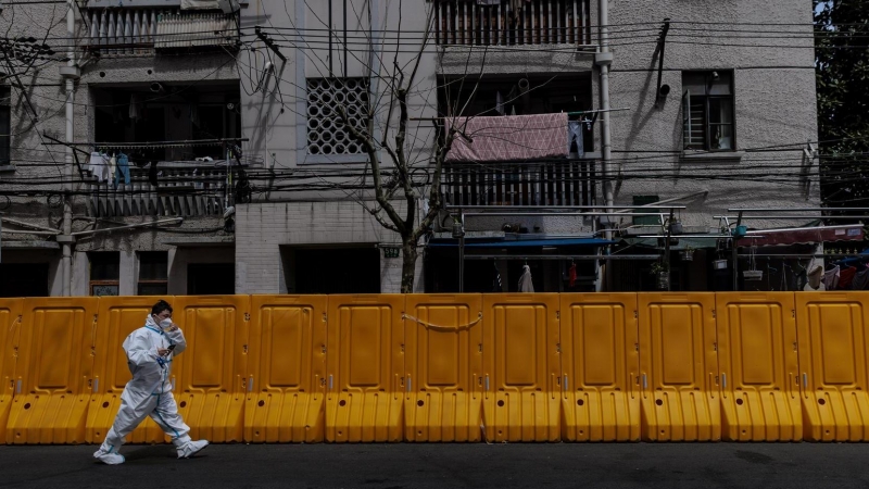 28/03/2022-Un hombre con equipo de protección camina frente al recinto en cuarentena, en Shanghai, China, el 28 de marzo de 2022