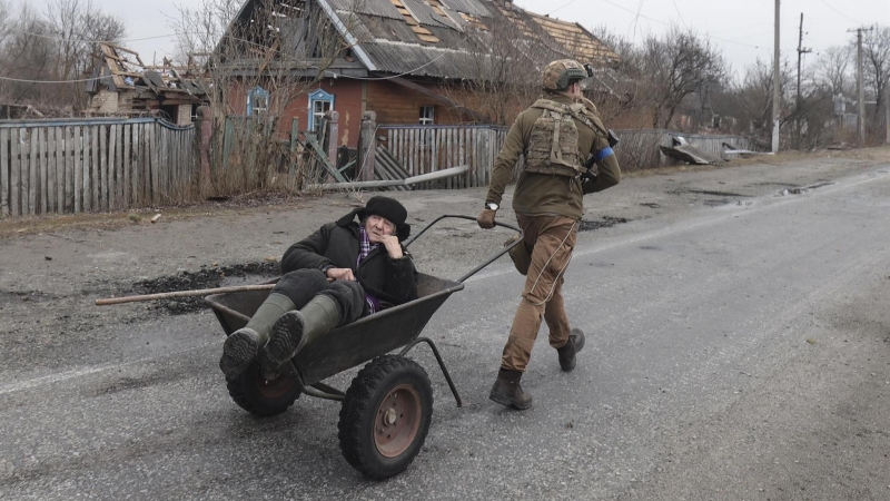 Un soldado ucraniano traslada en una carretilla a una persona mayor en la localidad de Teteriv, cerca de la capital Kiev, este 31 de marzo de 2022.