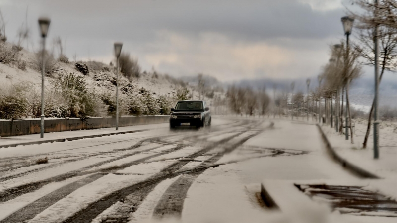 VITORIA, 02/04/2022.- Un coche circula por una carretera periférica de la ciudad de Vitoria que amanecía cubierta de nieve tras las nevadas caídas durante la noche