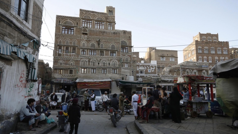 Yemeníes caminan frente a edificios antiguos, un día después de que las partes en conflicto acordaran una tregua de dos meses, en la ciudad vieja de Sana'Äôa, Yemen, el 2 de abril de 2022. Una tregua prorrogable de dos meses en Yemen entró en vigor el 2 d