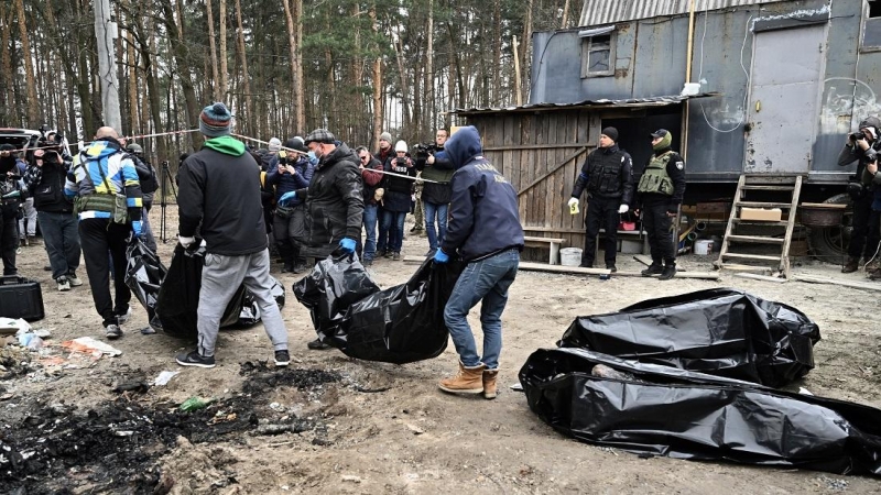 Los trabajadores de la ciudad llevan bolsas para cadáveres con seis cuerpos parcialmente quemados encontrados en la ciudad de Bucha el 5 de abril de 2022, ya que las autoridades ucranianas dicen que se han recuperado más de 400 cuerpos civiles de la regió