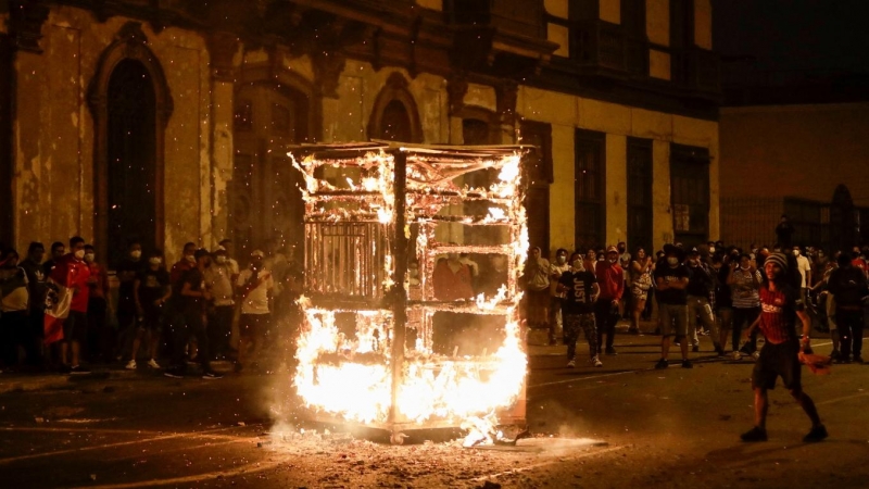 06/04/2022 - Manifestantes observan cómo arde la estructura de un vendedor ambulante durante una protesta contra el presidente de Perú, Pedro Castillo, después de que éste decretara el toque de queda que fue levantado tras el desafío generalizado en las c