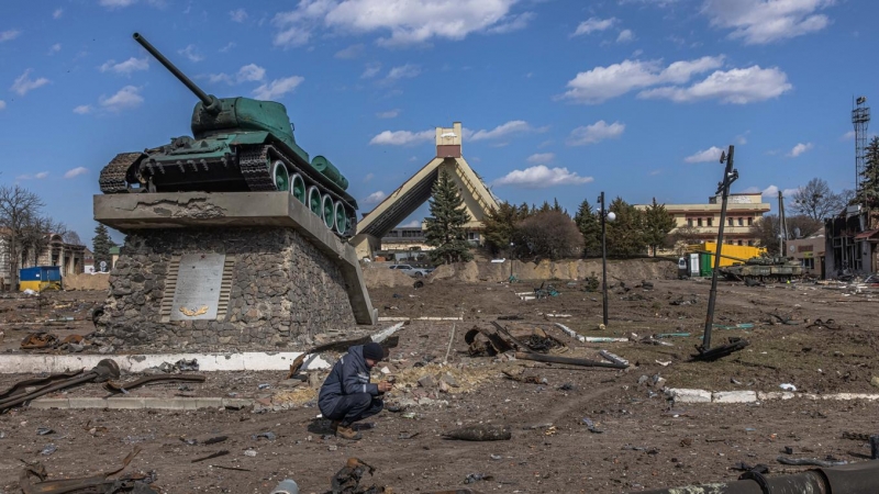 Un rescatista ucraniano examina un objeto explosivo junto a partes de vehículos militares rusos destruidos en el suelo frente a la estación de tren donde estaban estacionadas las fuerzas rusas, en la ciudad de Trostyanets, recapturada por el ejército ucra