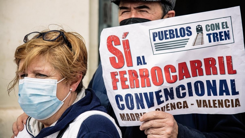 Dos personas sostienen una pancarta que reza 'Pueblos con el tren, Sí al ferrocarril convencional', en una manifestación de Aranjuez por el mantenimiento de la línea Valencia-Cuenca-Madrid.