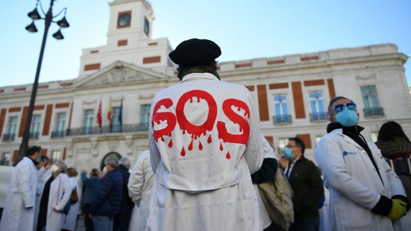 Un hombre con una bata donde se puede leer 'SOS' en una concentración en defensa de la Atención Primaria, a 13 de noviembre de 2021, en Madrid