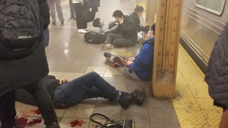 Personas heridas sentadas y tumbadas en el andén con manchas de sangre de la estación de metro de la calle 36 de Brooklyn, donde un hombre ha provocado un tiroteo este 12 de abril de 2022.