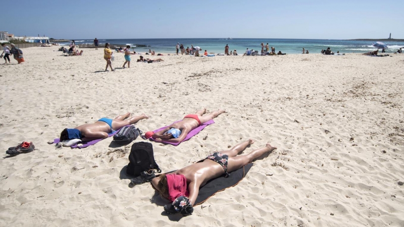 16/04/2022 Varias personas disfrutan de una jornada soleada en la playa de Punta Prima, Menorca, este Sábado Santo