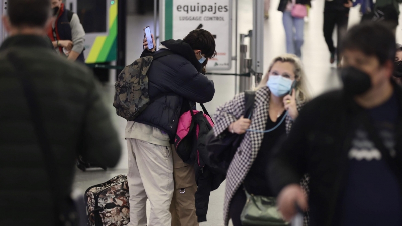 Dos personas, con maletas, se abrazan junto al control de equipajes, en el día en que arranca la operación salida de Semana Santa 2022, en la estación Madrid - Puerta de Atocha