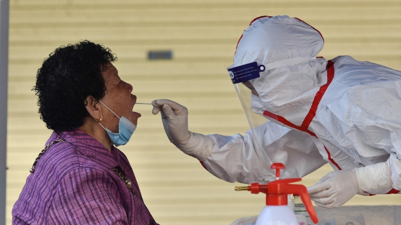 Un trabajador de la salud que usa un equipo de protección personal recolecta muestras de hisopos de un residente (18/4/21)