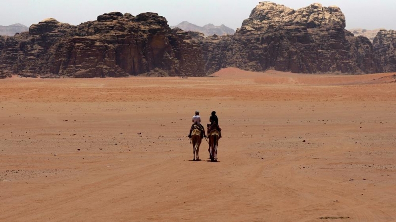 En el desierto de Wadi Rum, en Jordania, un beduino acompaña a un turista en camello.