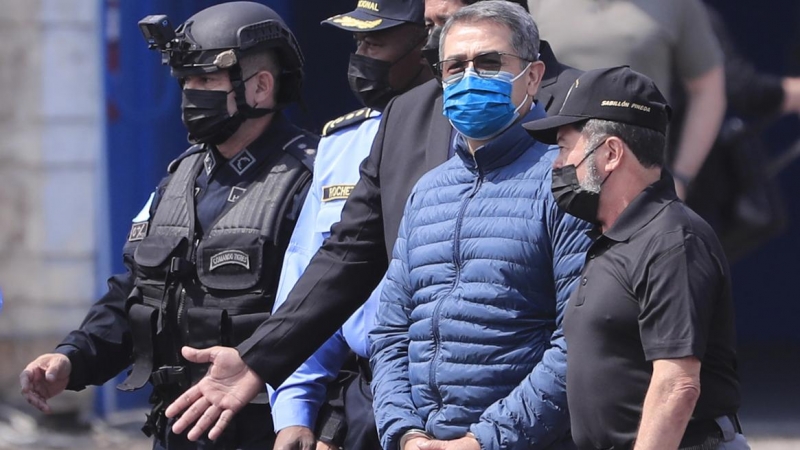 22/04/2022 - El expresidente hondureño Juan Orlando Hernández es dirigido a la aeronave que lo llevará extraditado a los Estados Unidos hoy, en la base aérea Hernán Acosta de Tegucigalpa (Honduras).