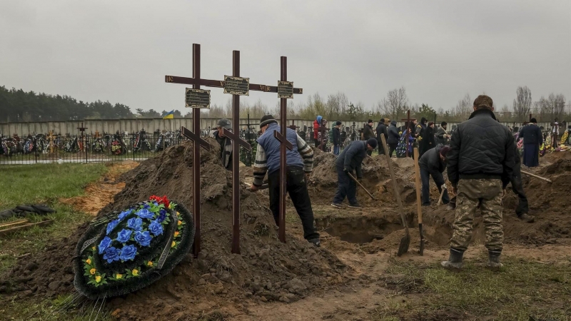 Varias personas entierran un cuerpo en el cementerio de Bucha (Ucrania) el 22 de abril de 2022.