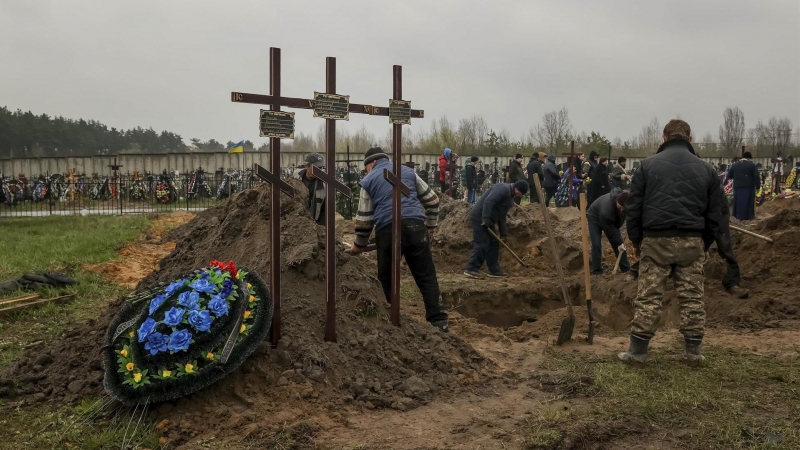 Varias personas entierran un cuerpo en el cementerio de Bucha (Ucrania) el 22 de abril de 2022.