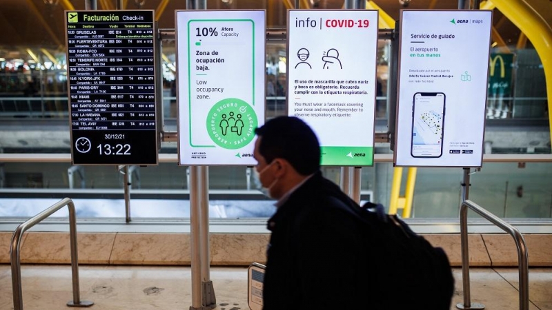 28/04/2022. Una persona pasa delante de unos paneles con las medidas de seguridad covid en la Terminal 4 del Aeropuerto Adolfo Suárez-Madrid Barajas, a 30 de diciembre de 2021.