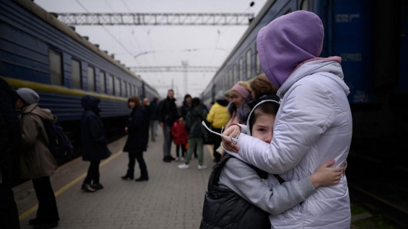 Una mujer abraza a un niño mientras un tren se prepara para salir de la estación principal de trenes en Zaporijia, en el sur de Ucrania, el 17 de abril de 2022.