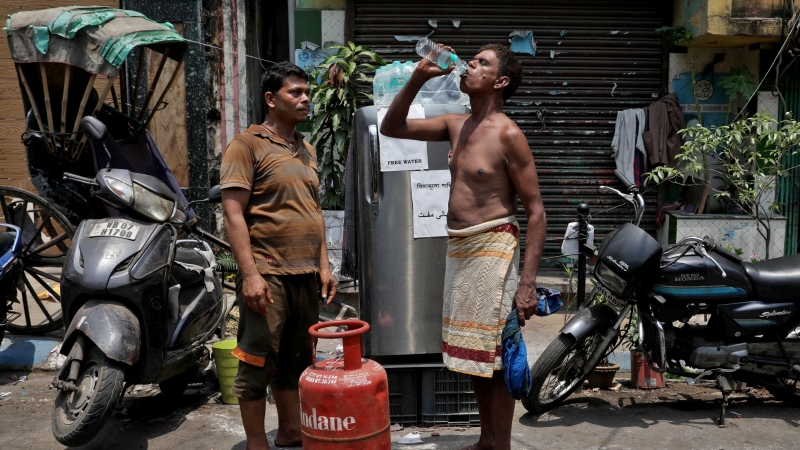 Un hombre bebe agua de una botella que sacó de una nevera instalada por un residente local junto a una carretera para distribuir agua fría gratis a los transeúntes, durante el clima cálido en Calcuta, India , el 26 de abril de 2022.