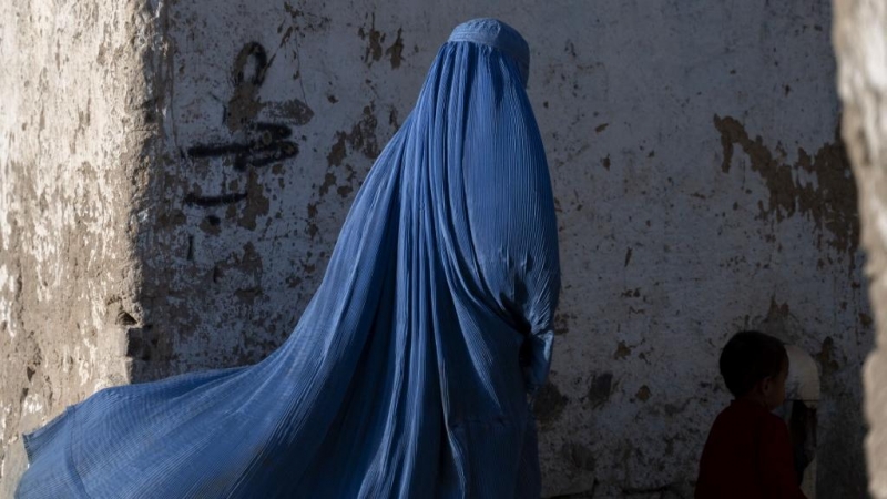 Una mujer afgana vestida con burka camina con un niño en Kabul el 28 de abril de 2022.