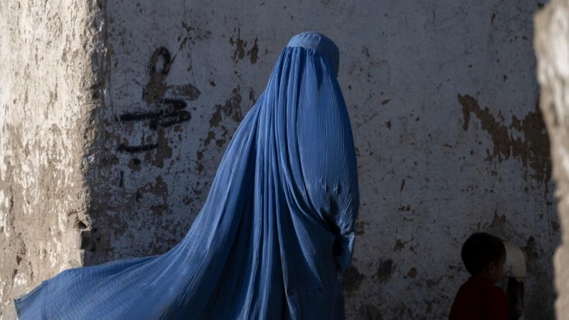 Una mujer afgana vestida con burka camina con un niño en Kabul el 28 de abril de 2022.