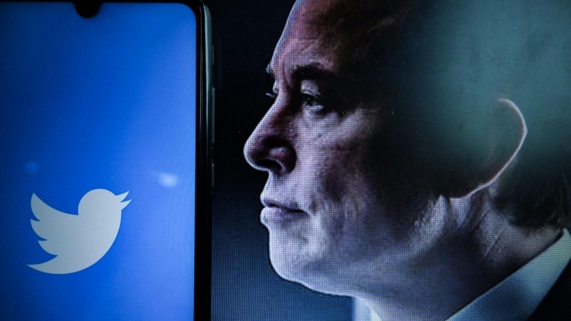 Una vista del logotipo de la empresa estadounidense de redes sociales Twitter en la pantalla de un teléfono inteligente junto a un retrato del empresario Elon Musk