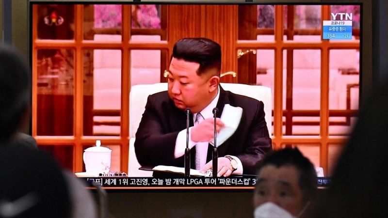 La gente se sienta cerca de una pantalla que muestra una transmisión de noticias en una estación de tren en Seúl el 12 de mayo de 2022, del líder de Corea del Norte, Kim Jong Un, quitándose una máscara facial en la televisión para ordenar cierres en todo