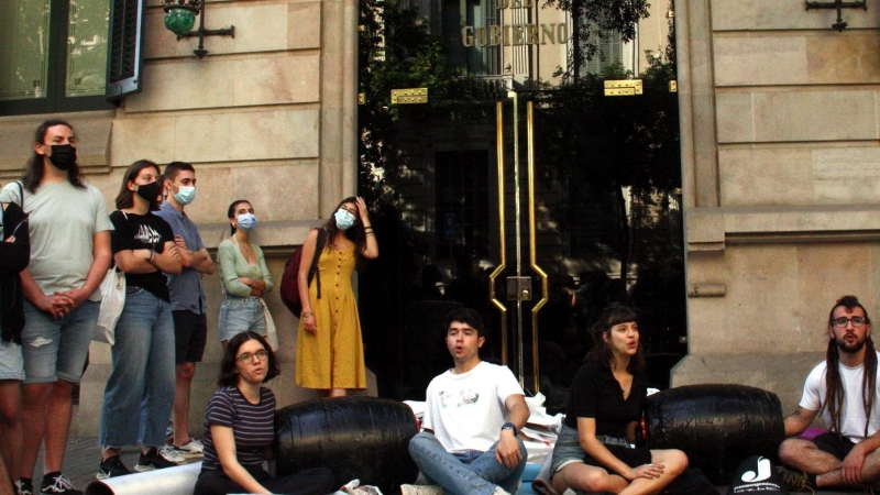 Quatre estudiants asseguts a terra i encadenats davant la delegació del Govern espanyol a Catalunya.