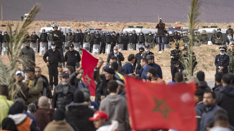 Las fuerzas de seguridad marroquíes montan guardia mientras los agricultores marroquíes protestan en la ciudad de Figuig el 18 de marzo de 2021, después de que las autoridades argelinas expulsaran a los cultivadores de dátiles del territorio argelino, una