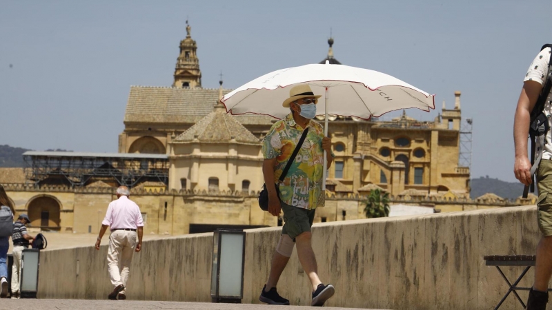 19/05/2022-Una persona se protege con una sombrilla del intenso calor mientras pasea este jueves 19 de marzo por el puente romano de Córdoba