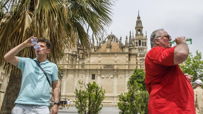 Turistas se refrescan en el centro de Sevilla en un día en el que las altas temperaturas son propias del verano.