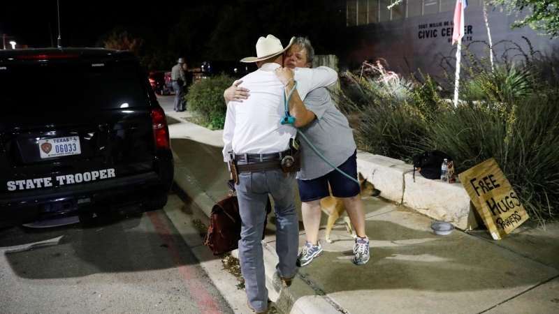 Una mujer que ofrece abrazos y oraciones abraza a un guardabosques de Texas fuera del Centro Cívico Ssgt Willie de Leon, donde los estudiantes habían sido transportados desde la Escuela Primaria Robb después de un tiroteo, en Uvalde, Texas , EE. UU. 24 de