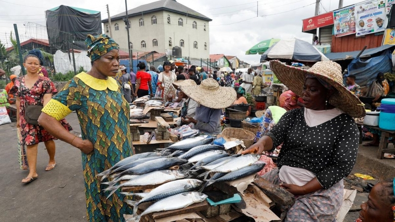 Una mujer habla con una vendedora de pescado en un mercado de Lagos, Nigeria