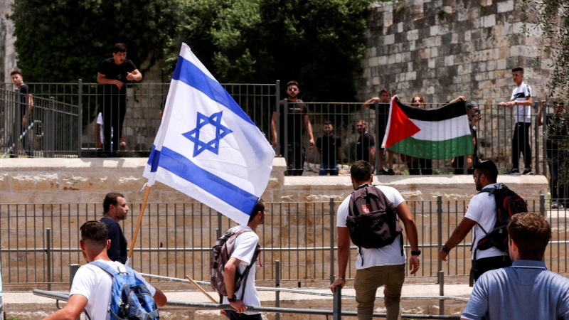 Los israelíes se paran con una bandera israelí frente a los palestinos con la bandera palestina junto a la puerta de Damasco a la Ciudad Vieja de Jerusalén el 29 de mayo de 2022.