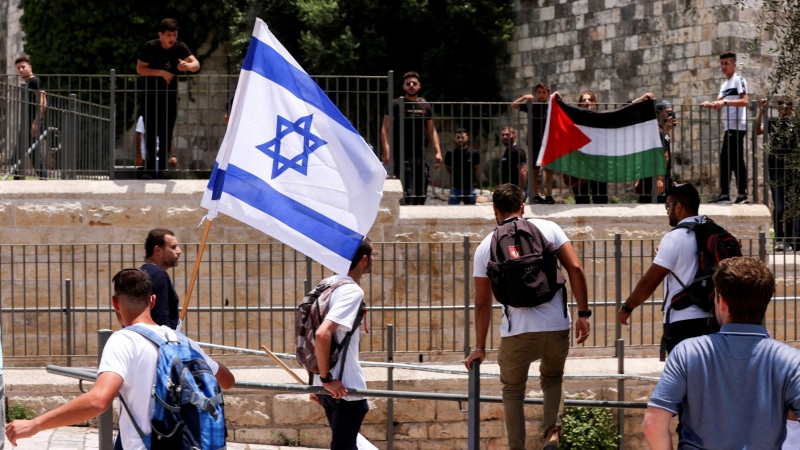 Los israelíes se paran con una bandera israelí frente a los palestinos con la bandera palestina junto a la puerta de Damasco a la Ciudad Vieja de Jerusalén el 29 de mayo de 2022.