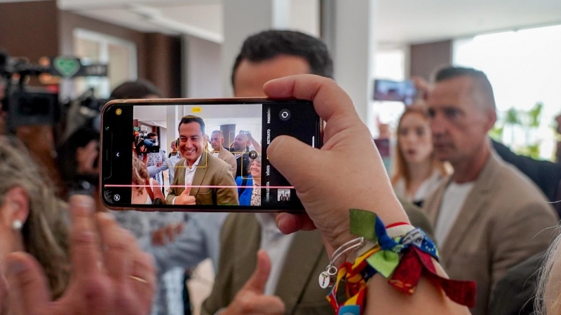 Una simpatizante saca una foto con su móvil al presidente de la Junta de Andalucía y candidato a la reelección, Juanma Moreno,  a su llegada a un acto público en Sevilla. E.P./Eduardo Briones