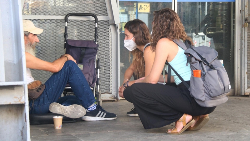 14/08/2021 - Dues treballadores de la Fundació Arrels atenen una persona sense llar a la Barceloneta, en una imatge del 2021.